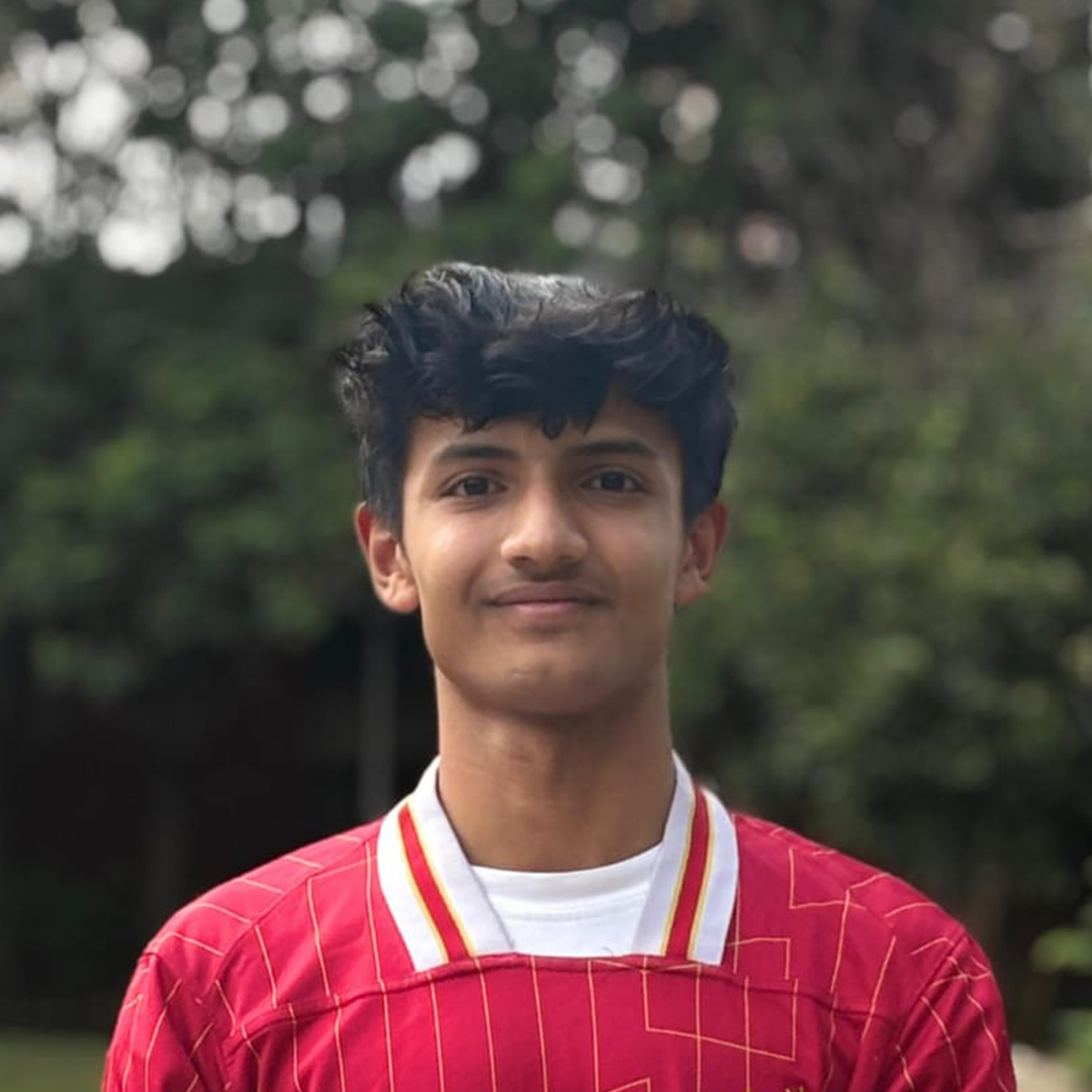 Outdoor portrait of a young man wearing a red striped sports jersey.