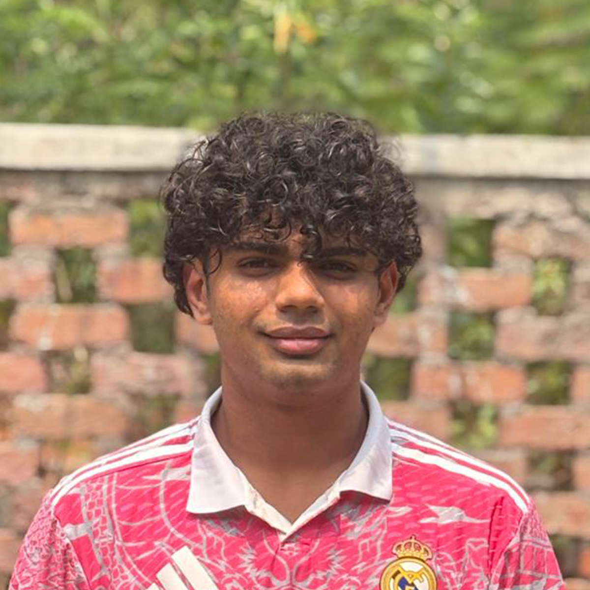 Outdoor portrait of a young man wearing a red patterned sports jersey.