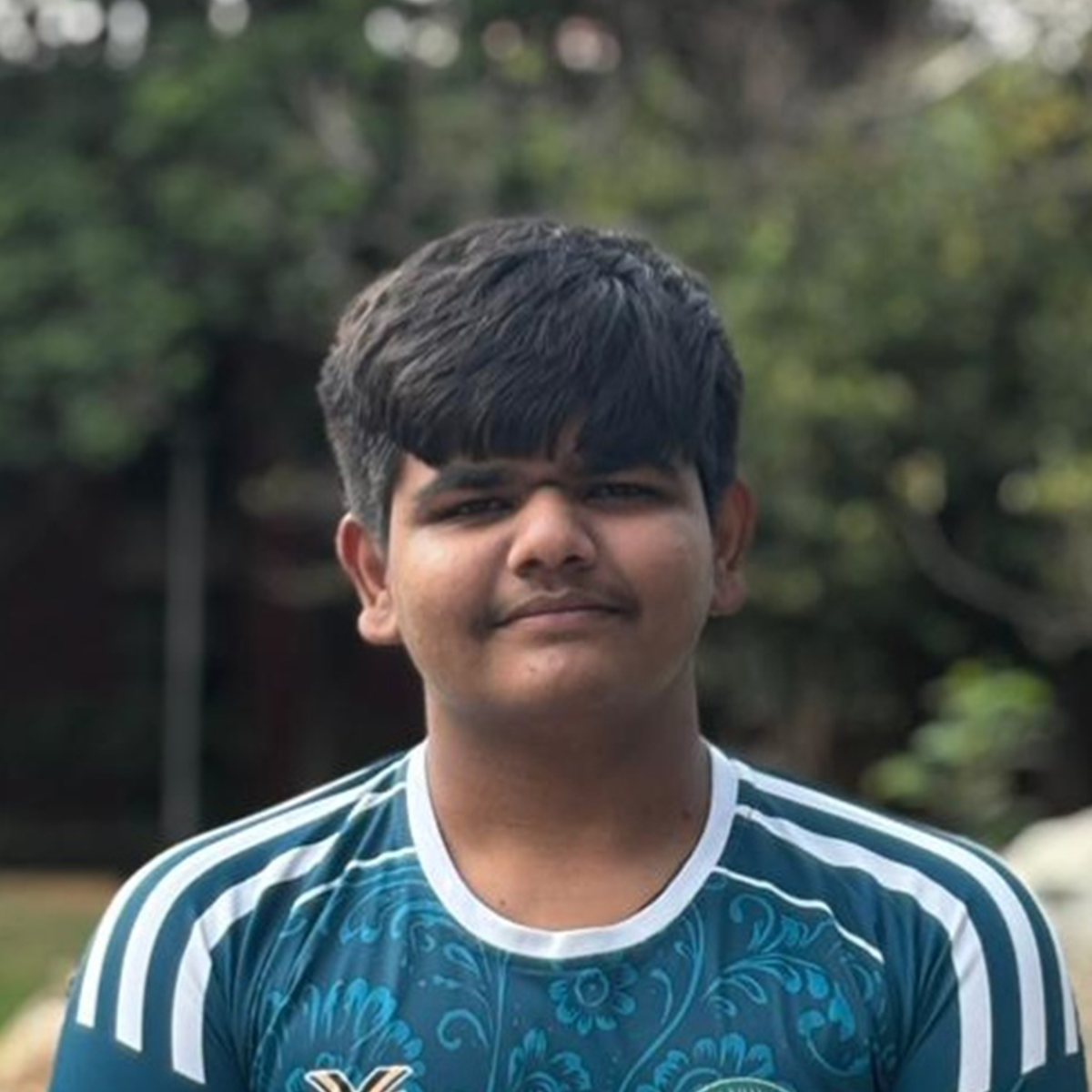 Outdoor portrait of a young man wearing a teal patterned sports jersey.