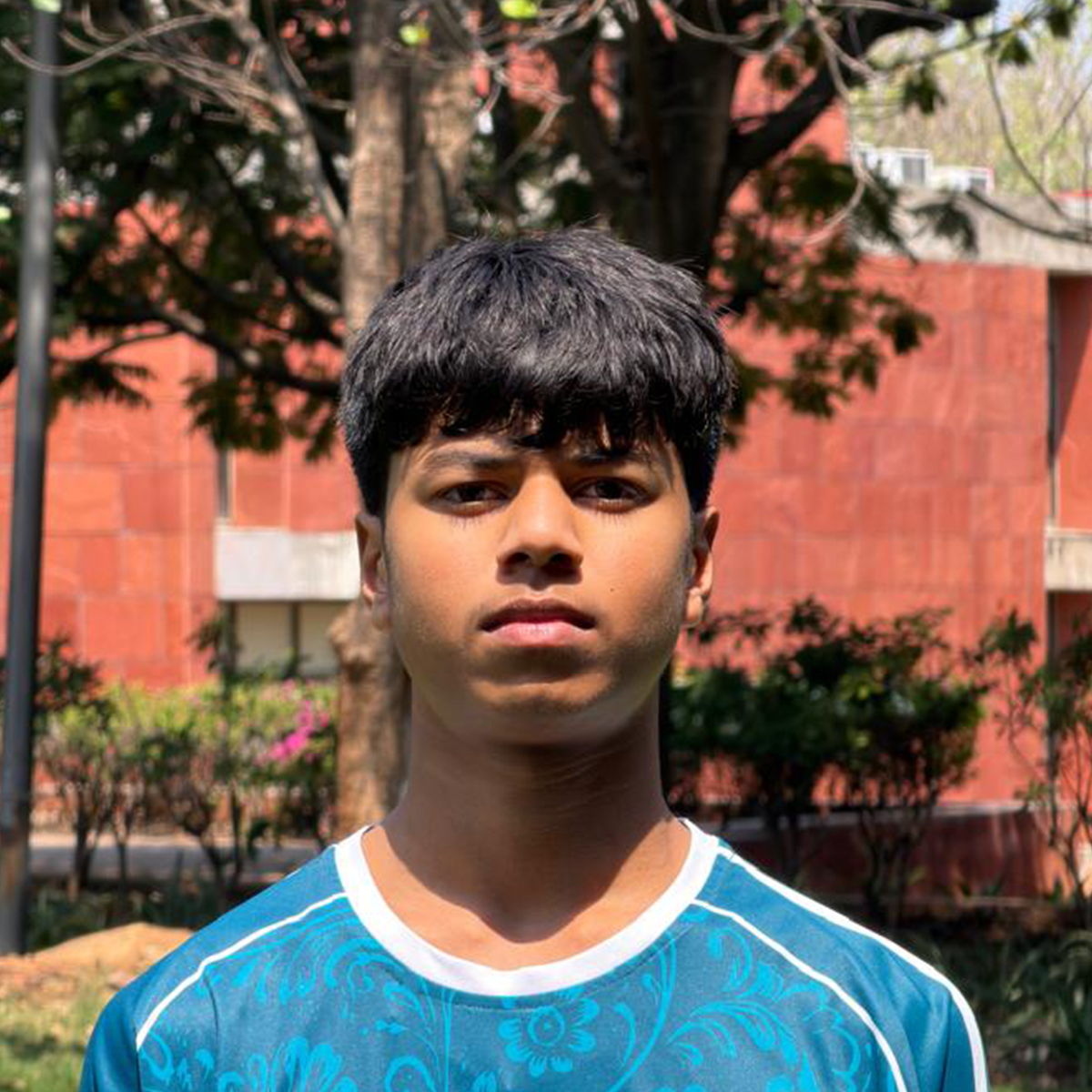 Outdoor portrait of a young man wearing a blue sports jersey.