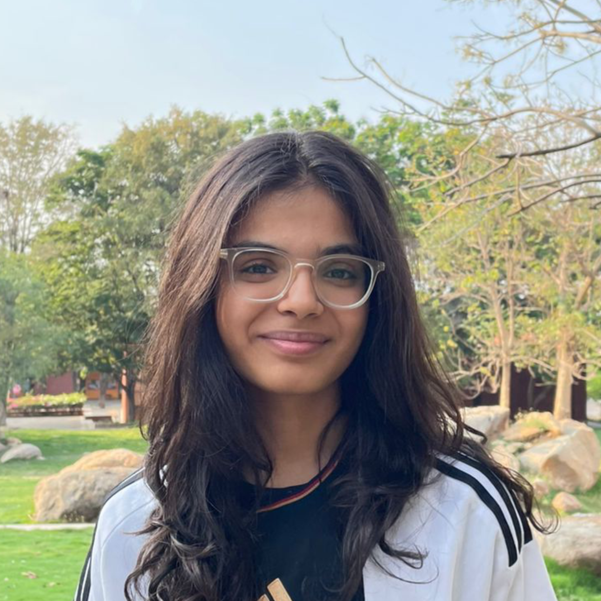 Outdoor portrait of a young woman wearing a white sports jersey.