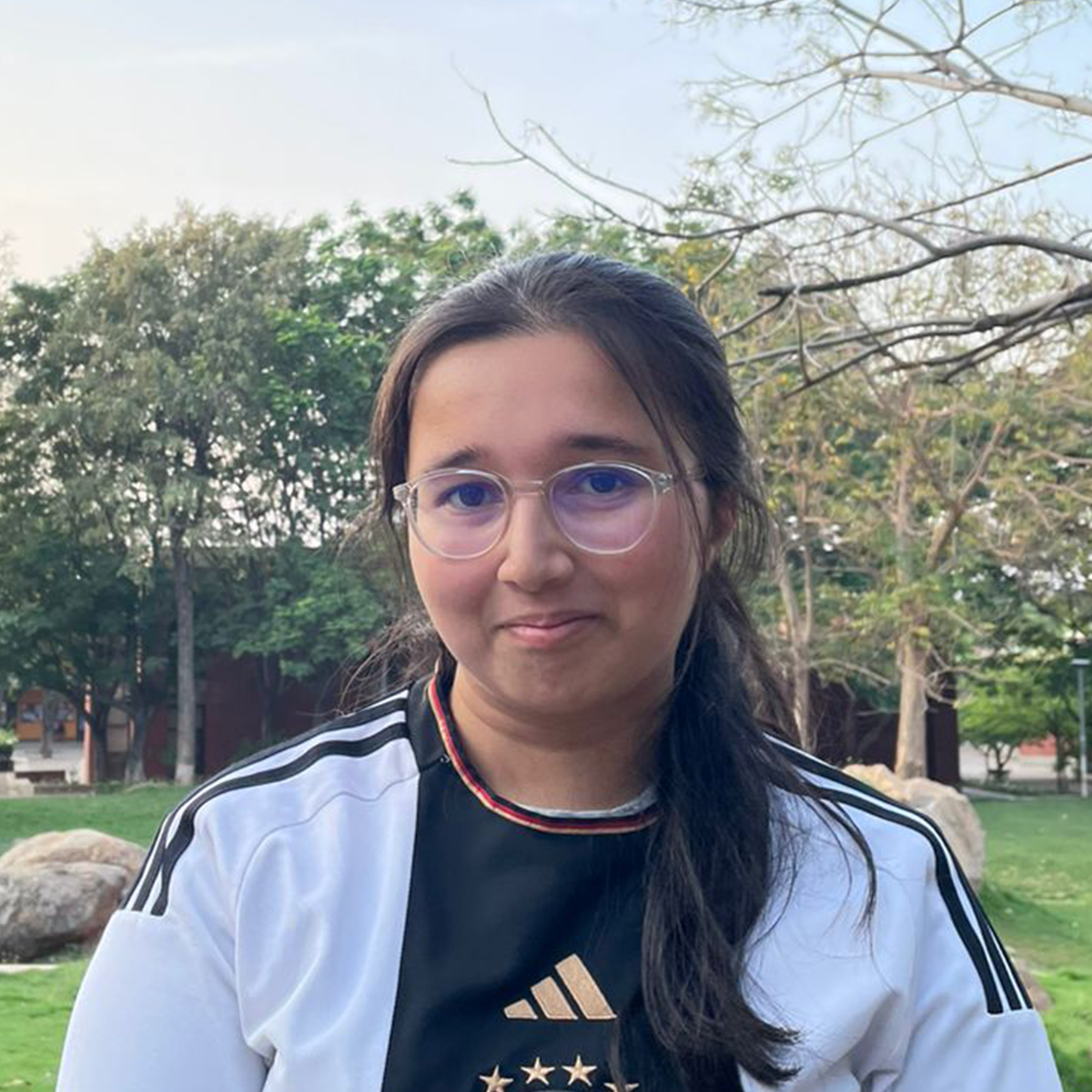 Outdoor portrait of a young woman wearing a white-and-black sports shirt.