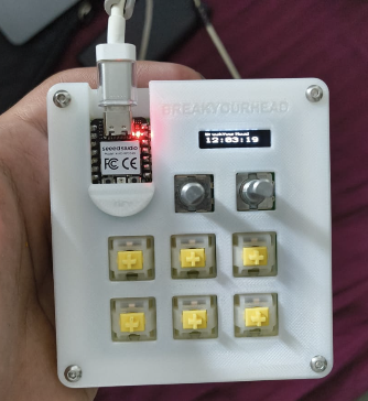 Photo of the assembled white Macropad with six yellow switches, two rotary encoders, a display, and USB cable.